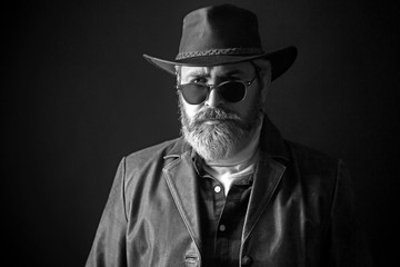 Sexy cowboy in a hat on the dark background.