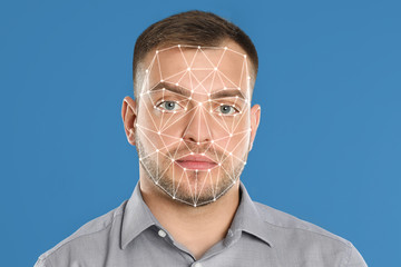 Facial recognition system. Young man with biometric identification scanning grid on light blue...