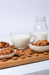 Almond milk in cup and bottle with nuts on white background