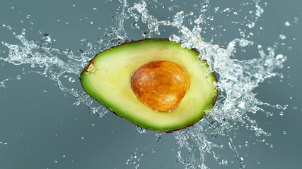 Freeze motion of sliced avocado with splashing water isolated on white background