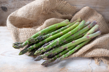 Organic green asparagus (Asparagus officinalis) fresh from the market on coarse burlap and rustic...