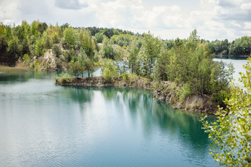 Lake on the background of rocks and fir trees. Canyon. The nature of spring, summer. Place for text and design. Landscape of an old flooded industrial granite quarry filled with water.