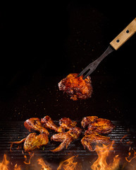 Tasty chicken legs and wings on the grill with fire flames