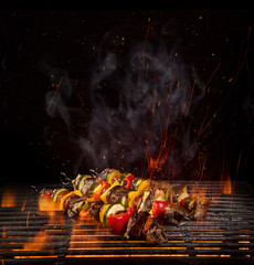 Tasty skewers on the grill with fire flames
