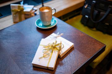 Naklejka na ściany i meble Cup of coffee with notebook gifts on wooden table