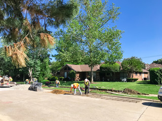Construction workers with mask repairing residential sidewalk in suburbs Dallas, Texas, USA