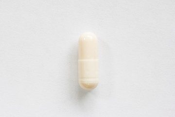 Cream colored medicine soft pill capsule macro close up shot isolated on white surface