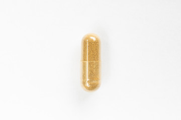 Brown colored medicine soft pill capsule macro close up shot isolated on white surface