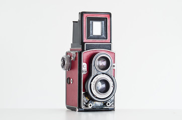 Vintage twin reflex red leatherette film camera with removed branding close up front side view shot isolated on white