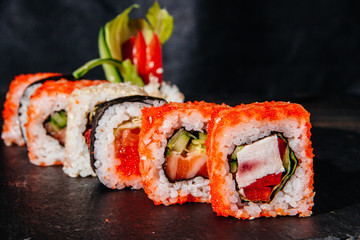 Beautiful and delicious variety of sushi rolls laid out on a stone board. - 344613456