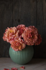 A bouquet of peach roses in a blue vase. Wooden copy space background.