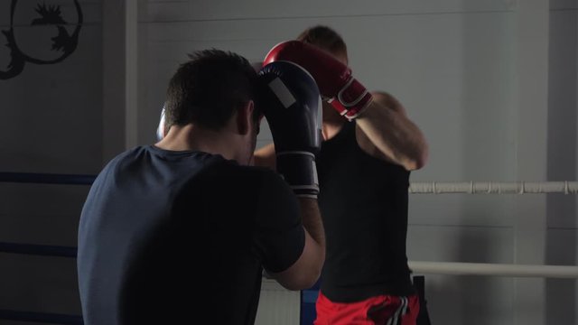 Muay thai sportsmen fighting at boxing ring. Athletic men fighting on a kickboxing match in a health club. Sport, competition concept