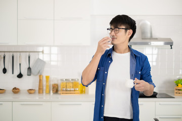 Asian man smelling good sauce cooking handmade in white kitchen.