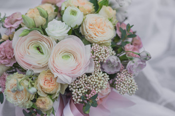 A large flower arrangement in a pink hat box was created by a florist for a wedding gift. White Freesia , pink Ranunculus asiaticus, eustoma flowers, roses and eucalyptus in a bouquet.
