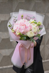 Stylish floral bouquet with pink hydrangea and Ranunculus asiaticus in contrasting pink wrapping paper. Designer flower bouquet from a florist
