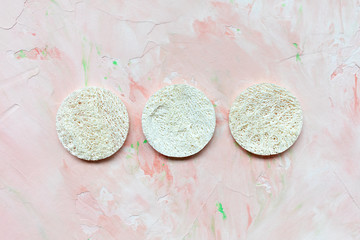 Three round loofah discs. Natural face sponges. Beauty treatment, plastic free and zero waste concept. Top view, copy space, pink background