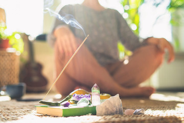 ?rystal and aroma stick burn. Woman doing yoga at home.