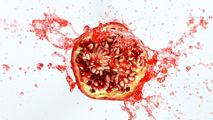 Freeze motion of sliced pomegranate with splashing juice isolated on white background