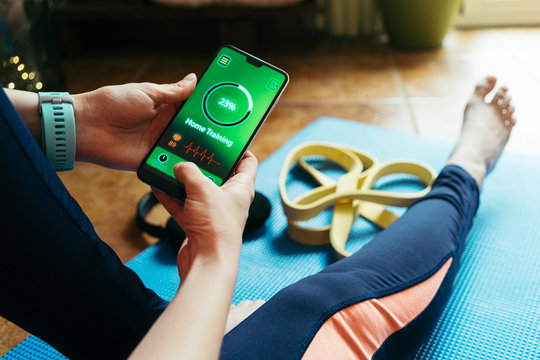 woman using smartphone during workout at home. Online personal trainer or on mobile phone. Internet fitness class or video course. Taking a break.