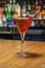 Cocktail prepared, on wooden table and bar background, with bottles and lights.