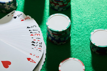 high angle view of playing cards with casino chips on green background