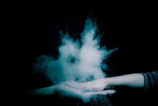 High five with two people hands and dust expolsion on black background