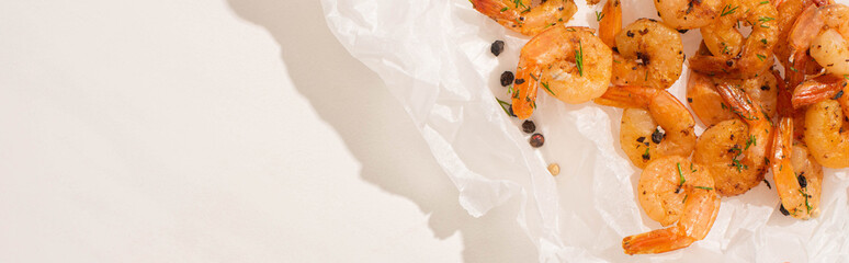 top view of fried shrimps on parchment paper with pepper on white background, panoramic shot