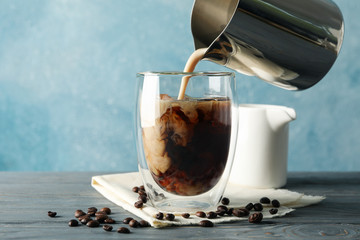 Milk is poured into a glass of coffee. Composition with ice coffee