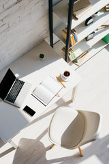 top view of home office with laptop, smartphone and cup of coffee in sunlight