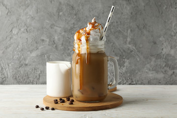 Iced coffee with poured cream on white wooden background
