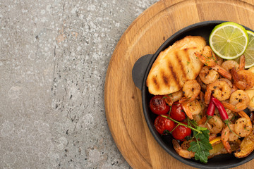 top view of fried shrimps with grilled toasts, vegetables and lime on grey concrete background