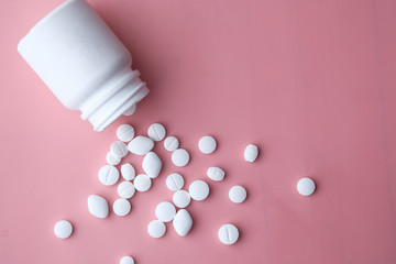 bottle of white pills on pink background 