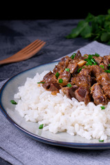 Stewed chicken gizzards on the boiled rice. Hot meal with offal meat products