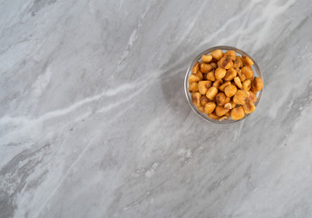 Organic corn nuts in a glass bowl offset on a gray countertop