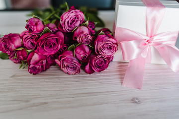 Gift box and pink roses on wooden background. Postcard. Space for text message. Flowers concept. Holiday greeting card for Valentines, Women's, Mother's Day, Easter. Happy Birthday. Wedding invitation