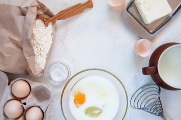 Ingredients for making dough for homemade pancakes for breakfast. On the table are wheat flour, eggs, butter, sugar, salt, milk. Selective focus. Sequencing