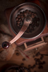 Old vintage manual coffee grinder with coffee beans on wooden background