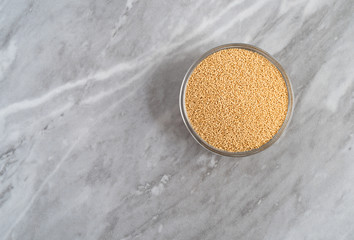 Bowl of organic amaranth seeds on a marble countertop top view