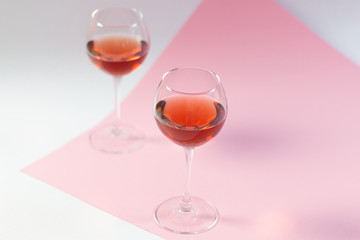 TWo glasses with rose wine standing on white and pink background