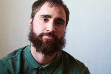 Fototapeta premium Portrait of young guy with dark beard with various emotions on his face in green shirt.