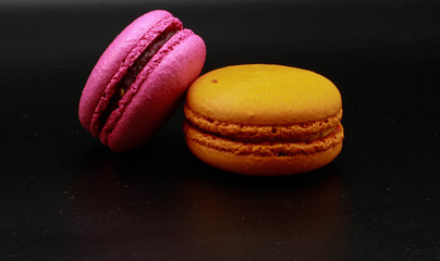 Pink and orange macarons. Black background.