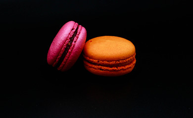 Pink and orange macarons. Black background.