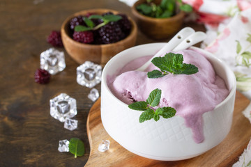 Homemade Organic Ice Cream with Mint. Blackberry ice cream in white bowl on a rustic table.