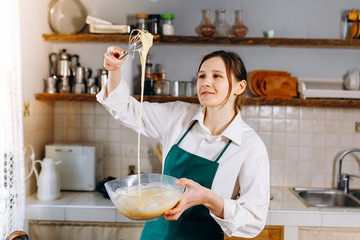 Young woman at the kitchen cooks Belgian waffles at home. Healthy Lifestyle. Cooking At Home. 