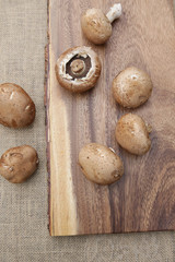 Fototapeta na wymiar Flat lay fresh organic brown mushrooms champignon on a wooden board. Top view. Vertical photo. 