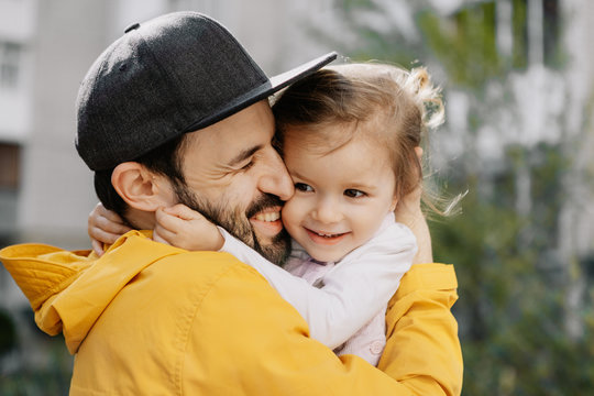 Portrait of a stylish pretty Father and his little daughter, they went for a walk on the playground in the courtyard of a multi-storey building