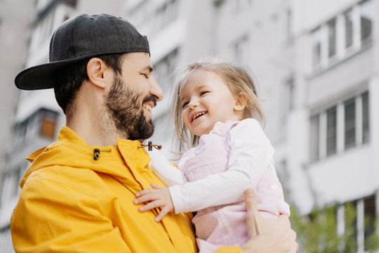Portrait of a stylish pretty Father and his little daughter, they went for a walk on the playground in the courtyard of a multi-storey building