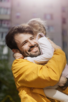 Portrait of a stylish pretty Father and his little daughter, they went for a walk on the playground in the courtyard of a multi-storey building
