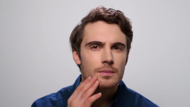 Man checking beard in studio. Bearded man touching face with hand