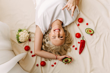 Obraz na płótnie Canvas Woman lying on the floor among vegetables. Concept of organic healthy food.
